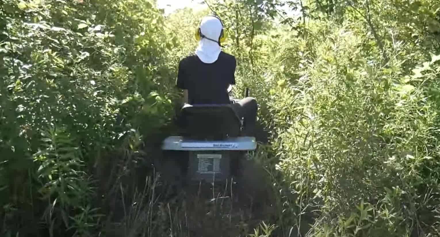 clearing brush with lawn garden tractor dense green brush on both sides man riding mower